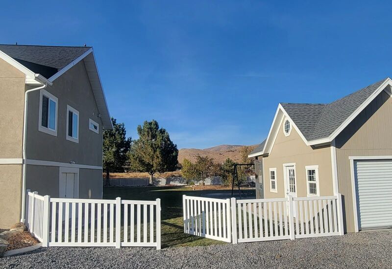 White vinyl closed picket fence with gate between two homes